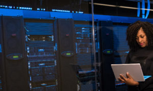 photographie illustrant une femme devant un parc informatique composé de serveurs
